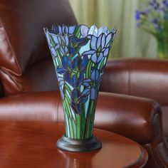 a glass vase sitting on top of a wooden table next to a brown leather chair