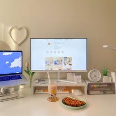 a desk with two computer monitors and a plate of food on the table next to it