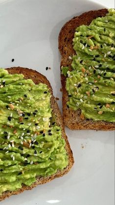 two pieces of bread with avocado spread on them sitting on a white plate