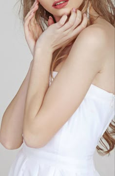 a woman in a white dress posing with her hand on her chin