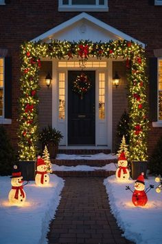 lighted snowmen in front of a house decorated for christmas