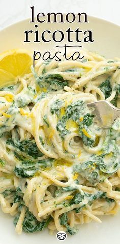 lemon ricotta pasta with spinach and pesto sauce on a white plate next to a lemon wedge