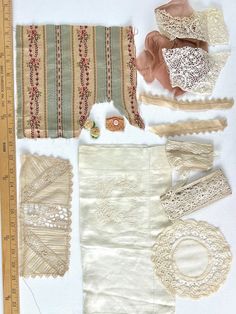 several pieces of cloth and lace laid out next to a measuring tape on a white surface