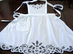 a white dress with lace on the bottom and an apron hanging from it's chest