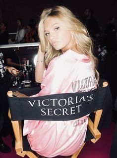 a woman sitting in a chair with a victoria's secret sign on her back