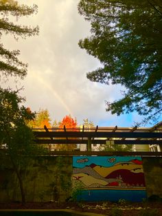 a bridge with a painting on it and trees in the background under a cloudy sky