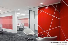 an office with red and white walls, chairs and desks in front of them