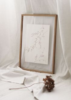 a pine cone is sitting next to an art piece on a white sheeted surface