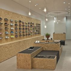 the inside of a shoe store with wooden shelves and shoes hanging on the wall behind them