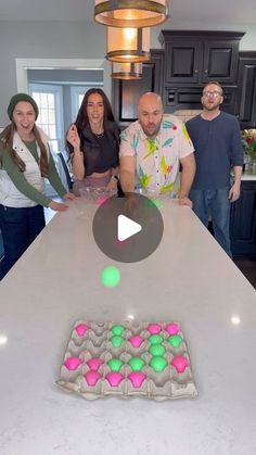 a group of people standing around a kitchen counter with a cake on top of it