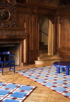 two blue chairs sitting in front of a fireplace