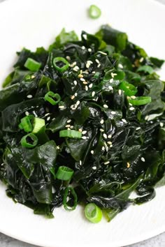 a white plate topped with greens and sesame seeds