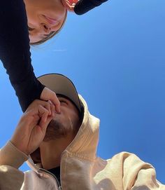 a man and woman standing next to each other in front of a blue sky holding hands