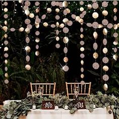 the table is set with white and pink decorations on it, along with two chairs that are facing each other