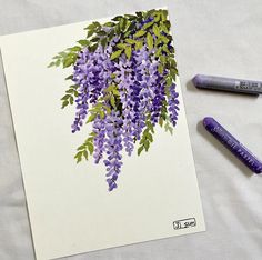 some crayons are laying on a sheet of paper with purple flowers and green leaves