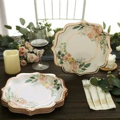 the table is set with plates, silverware and flowers in gold trimmings