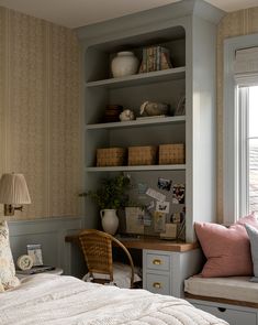 a bed sitting next to a window in a room with bookshelves on the wall