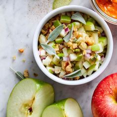 an apple and other fruits are on the table with some seasoning next to them