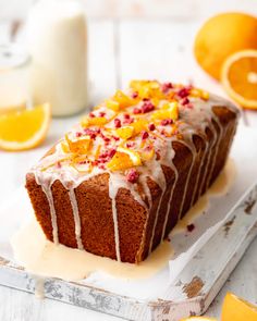 a close up of a cake on a tray with oranges and milk in the background