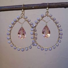 a pair of earrings with pink stones and pearls hanging from it's hooks on a branch