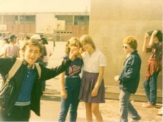 a group of young people standing next to each other near a building with their arms in the air