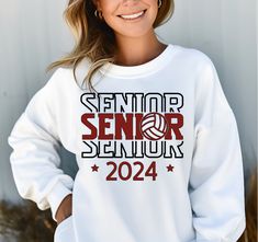 a woman wearing a white sweatshirt with the words senior senior on it and a volleyball ball