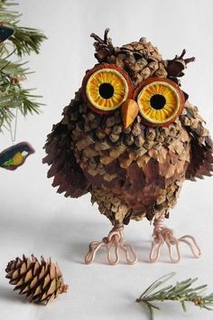 an owl figurine made out of pine cones and other things sitting next to it