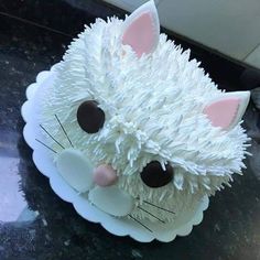 a cake with white frosting on top of a black counter topped with a cat face