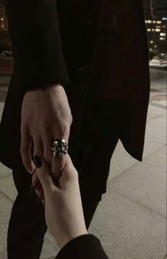 a man and woman holding hands while walking down the street