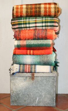 a stack of blankets sitting on top of a metal container next to a wall and floor