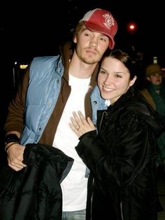 a man standing next to a woman wearing a red hat and blue jacket at night