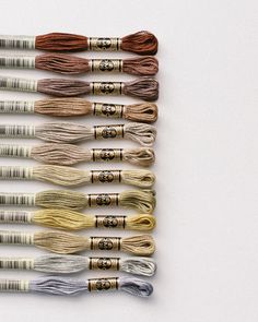 six skeins of different colors of thread on a white surface with gold and silver handles