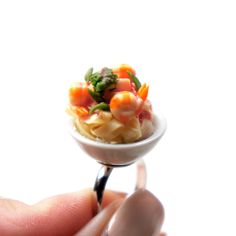 a miniature food item is being held by someone's hand with a tiny spoon