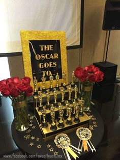 the oscar awards are on display with red roses in vases and an award plaque