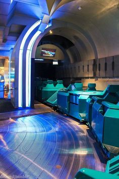 the inside of a train station with blue and green lights on it's walls