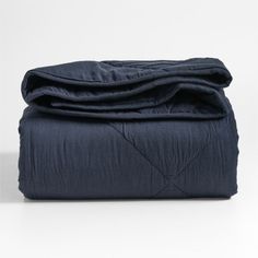 an unmade bed with dark blue sheets and blankets on the bottom, in front of a white background