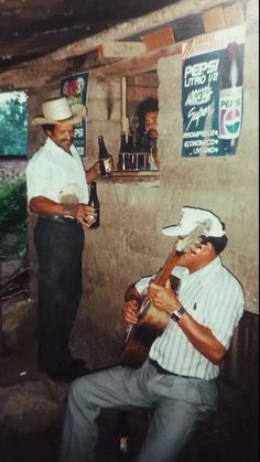 two men playing instruments in front of a bar