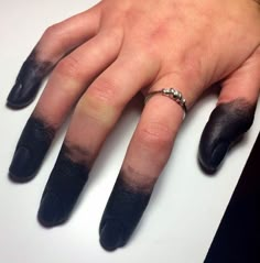 a woman's hand with black nail polish and ring on top of her finger