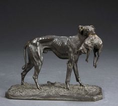 a bronze statue of a dog with its head on the back of it's neck