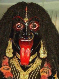 an elaborately decorated mask with long black hair and red lipstick on it's lips