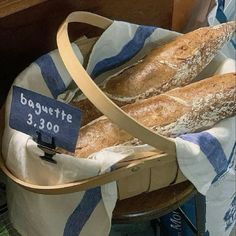 two loaves of bread sitting in a basket with a price sign on the side