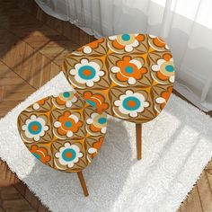 two chairs sitting on top of a white rug next to a table with an orange and blue flower design