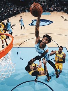 the basketball player is going to dunk the ball into the hoop while other players watch