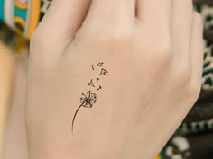 a woman's hand with a dandelion tattoo on it