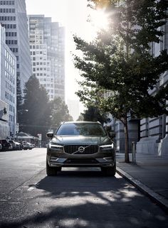 a volvo car is parked on the street in front of some tall buildings and trees