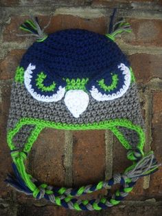 a crocheted hat with an owl's face on it sitting on top of a brick wall