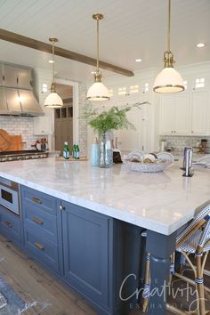 a large kitchen island with blue cabinets and white marble counter tops, surrounded by stools