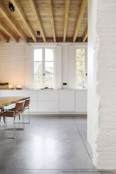 an empty kitchen with white walls and wooden beams on the ceiling is seen in this image