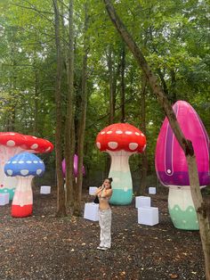 a man taking a photo in front of some mushroom shaped structures with trees and bushes behind him