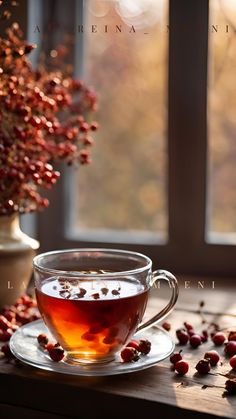 a cup of tea on a saucer next to berries